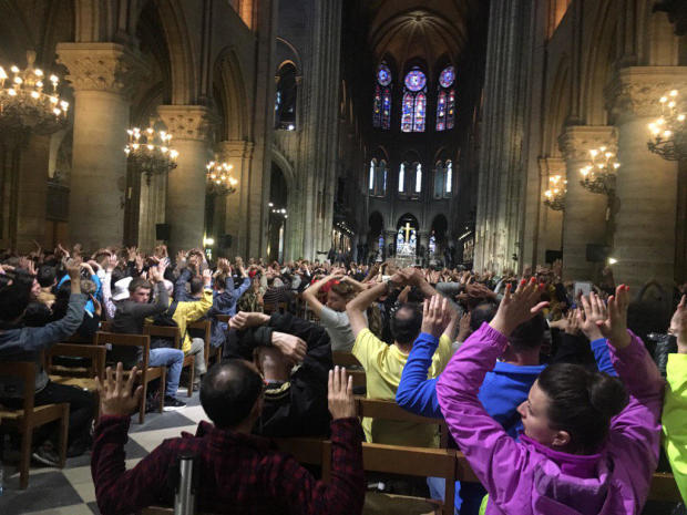 Visitors to Notre Dame Cathedral raise their hands during a security operation after a man attacked police officers with a hammer outside the cathedral in Paris on June 6, 2017. 