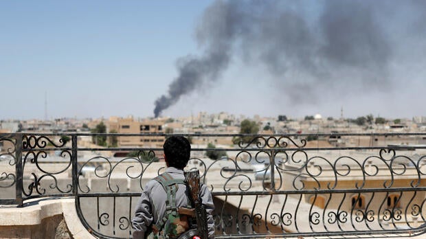 A Kurdish fighter from the People's Protection Units looks at a pillar of smoke after a coalition airstrike in Raqqa, Syria, June 16, 2017.