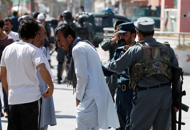 Afghan policemen try to comfort a man whose relatives were stuck at the site of a suicide attack followed by a clash between Afghan forces and insurgents after an attack on a Shi'ite Muslim mosque in Kabul