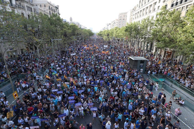 People hold signs and flags as they take part in a march of unity after the attacks last week, in Barcelona, Spain