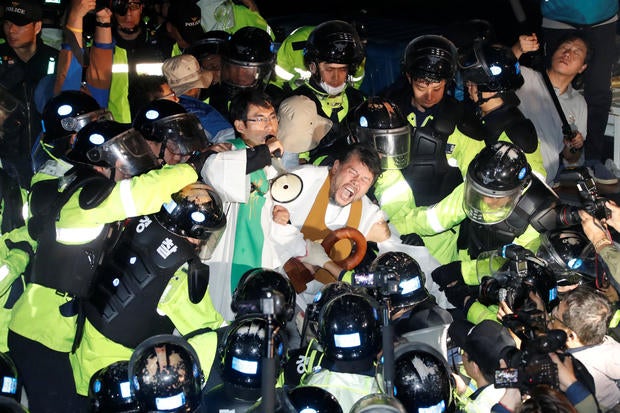 People scuffle with riot policemen during a protest opposing the deployment of a THAAD system in Seongju