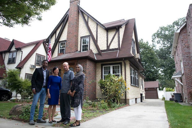 Abdi Iftin, left, of Somalia; Uyen Nguyen, second from left, of Vietnam; Eiman Ali, right, of Somalia but born in Yemen; and Ghassan al-Chahada of Syria pose for a photo outside President Trump's boyhood home in the Jamaica Estates neighborhood of the Que