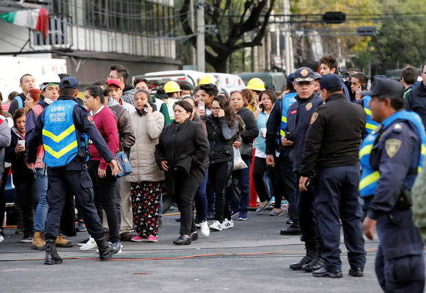 Police officers and people wait along the street after a tremor was felt in Mexico City 