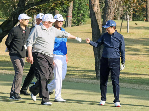 U.S. President Donald Trump gestures to Japan's Prime Minister Shinzo Abe as Japanese professional golfer Hideki Matsuyama looks on, as they play golf at the Kasumigaseki Country Club in Kawagoe, Japan 