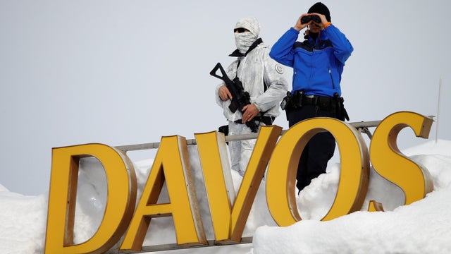 Swiss police officers observe the surrounding area from atop the roof of the Davos Congress Hotel during the World Economic Forum (WEF) annual meeting in Davos