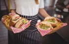 Midsection of waitress holding fresh fast food in wicker baskets 