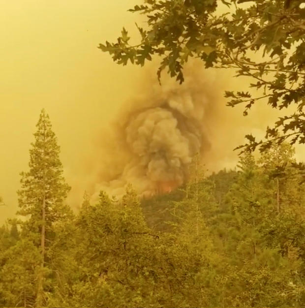 Flames and smoke rise from a treeline during a wildfire in Mariposa County, California 
