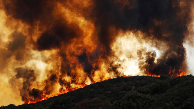 Wind-driven flames roll over a hill towards homes during the River Fire in Lakeport, California 