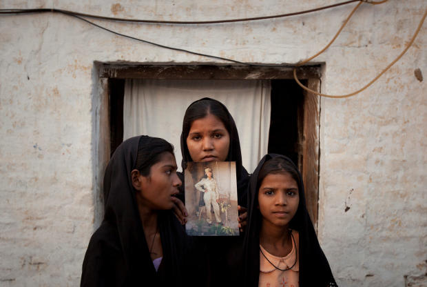 FILE PHOTO: The daughters of Pakistani Christian woman Asia Bibi pose with an image of their mother while standing outside their residence in Sheikhupura Pakistan 