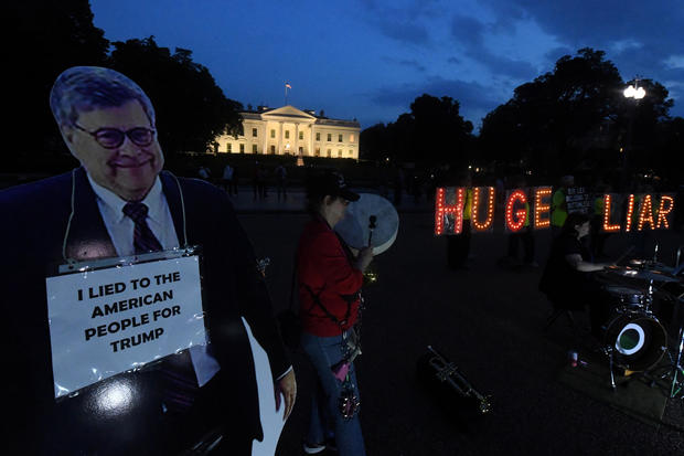 Protesters hold up letters beside a cardboard cutout of Attorney General Barr in Washington 