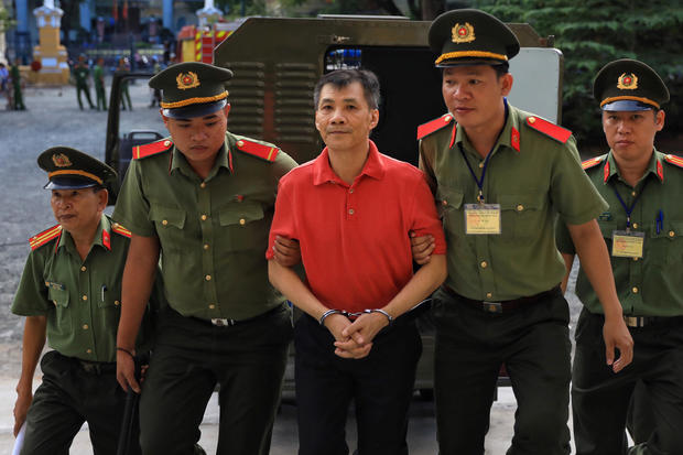 U.S. citizen Michael Nguyen is escorted by policemen before his trial at a court in Ho Chi Minh city 