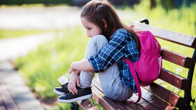 Unhappy schoolgirl sitting in the park. Education, lifestyle concept