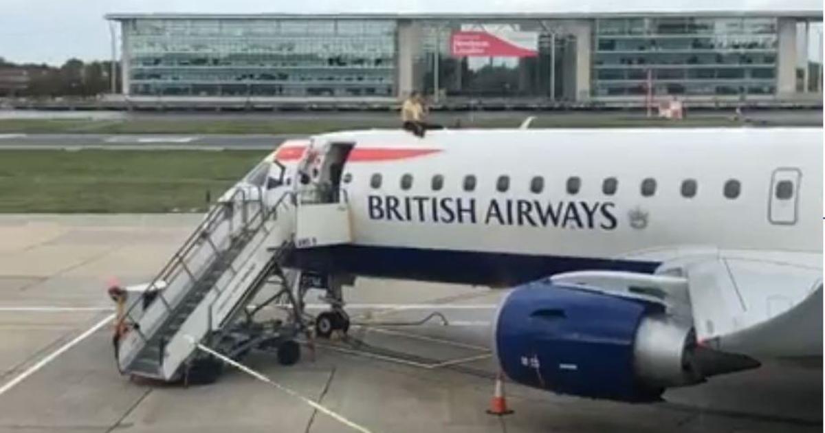 Climate change protester climbs on top of plane at London airport - CBS News