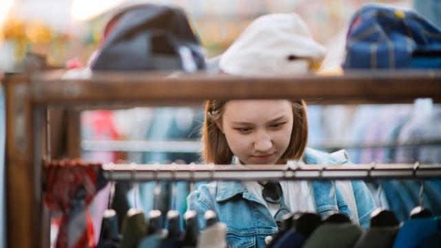 Young girl choosing clothes in a second hand market in summer, zero waste concept 
