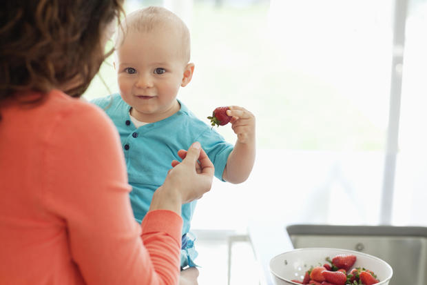 Mother giving baby strawberry 
