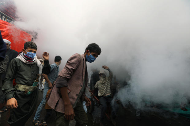 People wearing protective face masks react as health workers fumigate a market amid concerns of the spread of the coronavirus disease (COVID-19), in Sanaa 