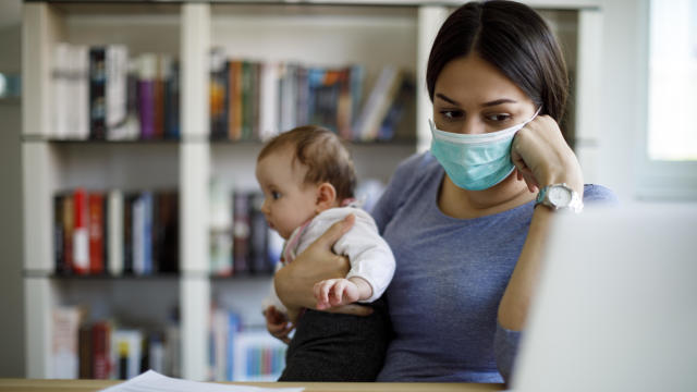Worried mother with face protective mask working from home 