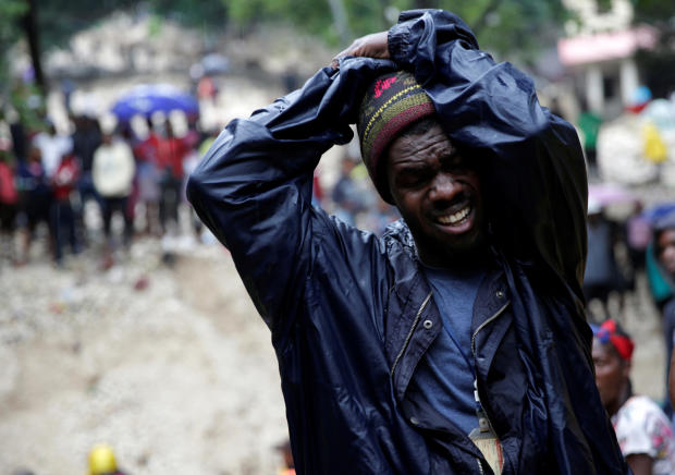 A man reacts in front of the body of his mother, who died during the passage of Tropical Storm Laura, in Port-au-Prince, Haiti, August 23, 2020. 