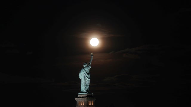The Harvest Moon Rises Behind the Statue of Liberty in New York City 