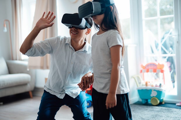 Father Using Virtual Reality Headset With His Daughter