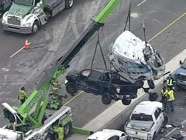 An image capture of aerial footage shows a crane lifting two vehicles from a massive pileup on Interstate 35 in Fort Worth, Texas, February 11, 2021.