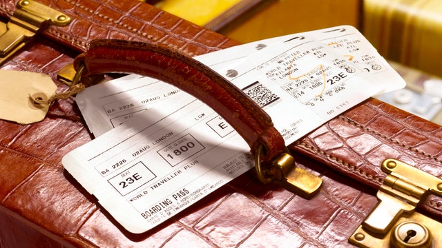 crocodile skin suitcase and boarding pass 