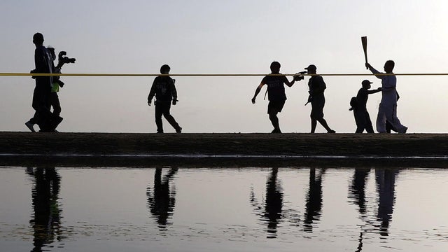 A Tokyo 2020 Olympic torch relay participant runs on a beach in Mitoyo in Kagawa Prefecture, western Japan