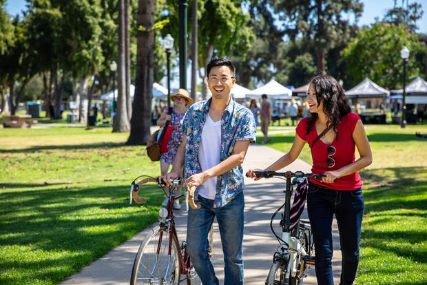 Los Angeles Couple Wheeling Bikes Through Park Durning Farmer's Market 