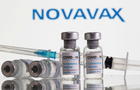 FILE PHOTO: Vials labelled "COVID-19 Coronavirus Vaccine" and syringe are seen in front of displayed Novavax logo in this illustration 