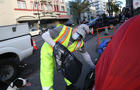 John Duport, Department of Public Works worker, hands a trash bag to someone in a tent on Hyde Street while cleaning the street and sidewalk on Wednesday, March 25, 2020 in San Francisco, Calif. 