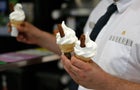 Three ice cream cones held by worker 
