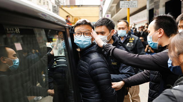 Stand News acting chief editor Patrick Lam is escorted by police as they leave after the police searched his office in Hong Kong 