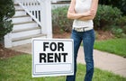 A young woman standing behind a ?for rent? sign 