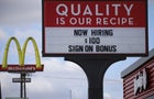 "Now hiring" sign with McDonald's sign in background 