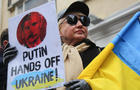 A protester holds a Ukrainian flag and a placard that says " 