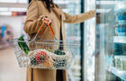 Cropped shot of woman carrying shopping basket and shopping groceries in supermarket 