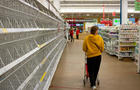 A woman walks by empty shelves in a supermarket in Moscow. 