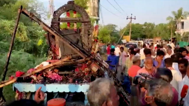 People gather around a chariot that was damaged after a high voltage power wire fell on it, killing at least 11 people, during a procession in a temple festival in Kalimedu village 