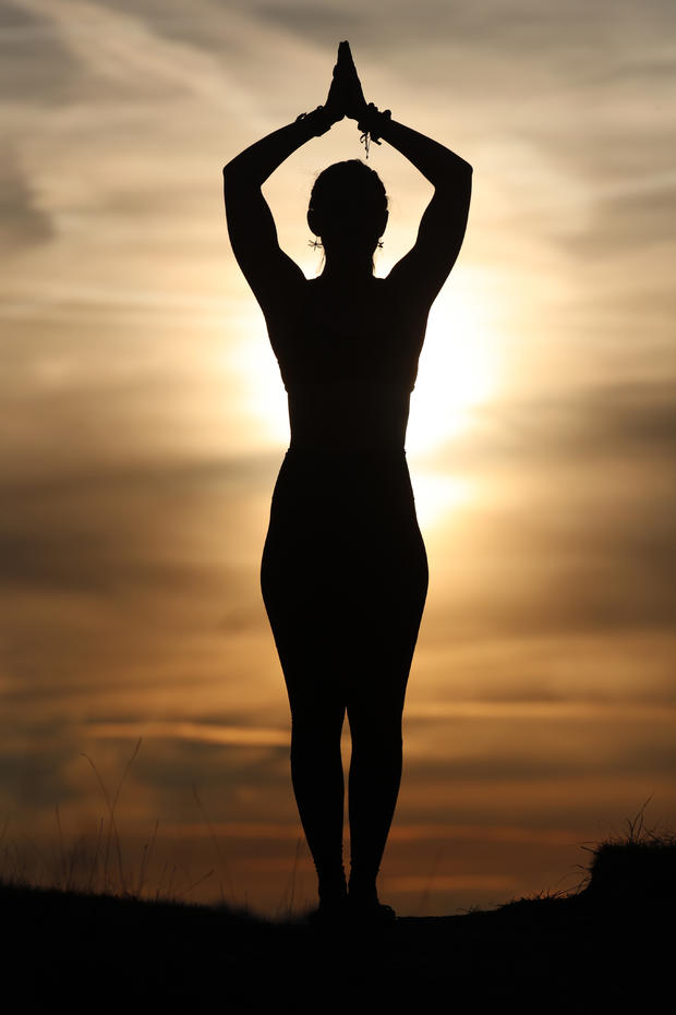 Silhouette of a woman practicing yoga against the light of the evening sun. Tadasana: the mountain pose. 