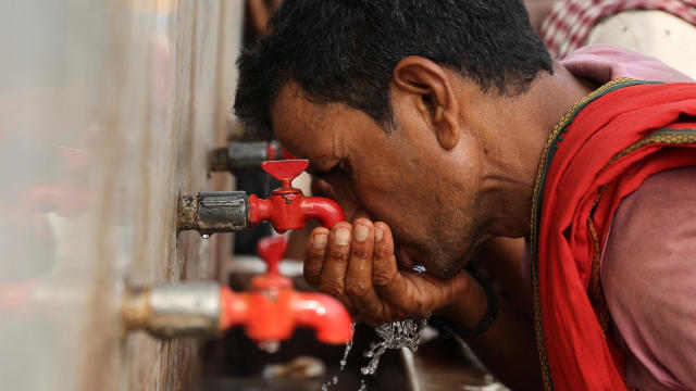 A laborer drinks from a public drinking water tap on a hot day in the old quarters of Delhi, India, May 4, 2022. 