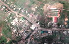 A satellite image shows damaged buildings and a tank on a road, in Lyman 