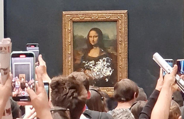 Visitors take a pictures and video of the painting "Mona Lisa" after cake was smeared on the protective glass at the Lourve Museum in Paris 