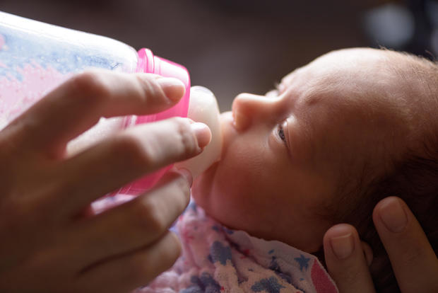 Mother feeds the newborn with bottle milk 